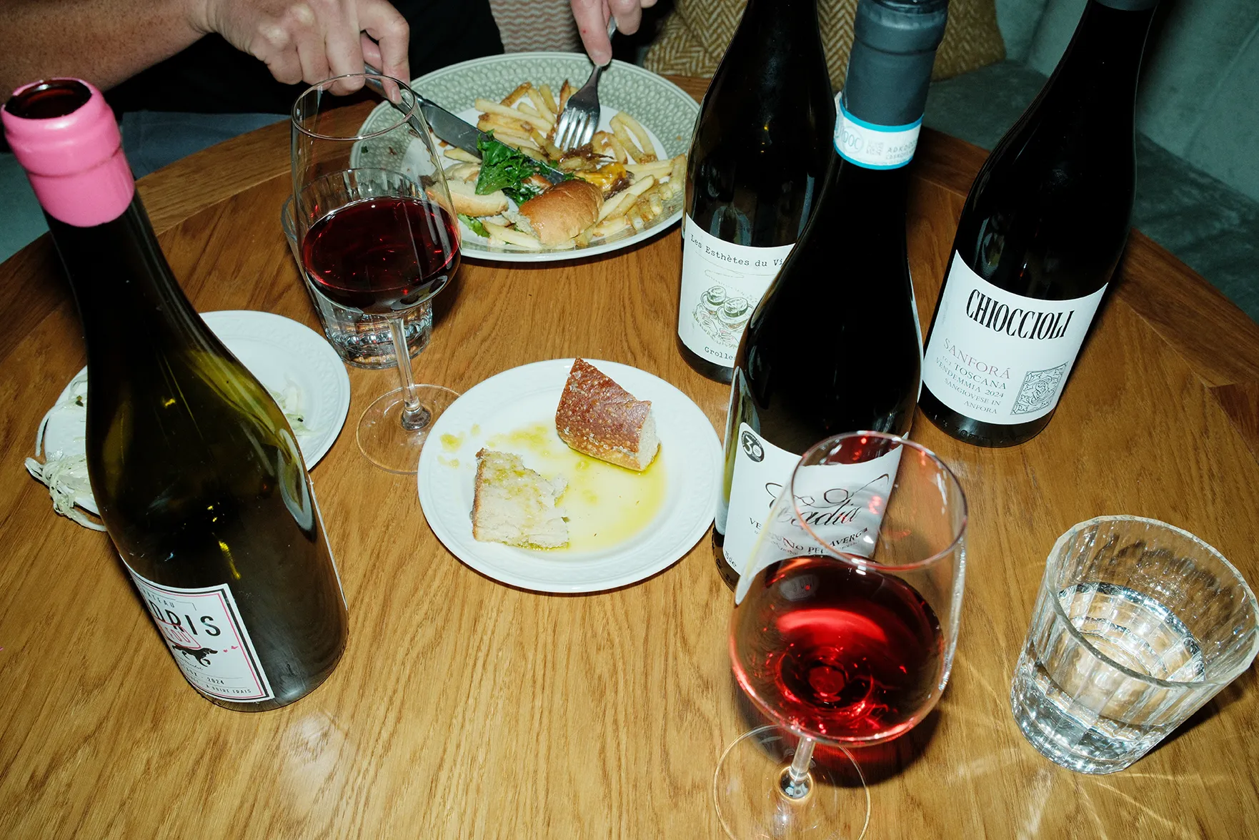 bild på mat och vin på ett bord och en person som äter